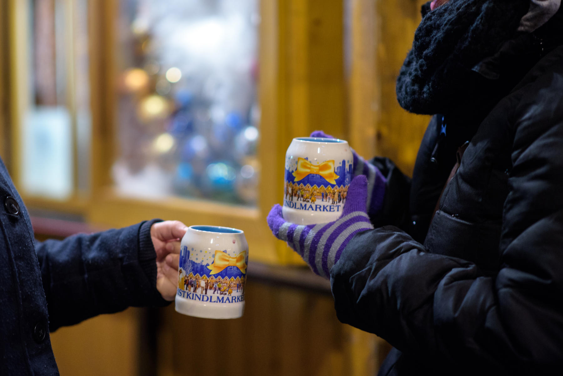 Two friends enjoy coffee in mugs at the Christkindlmarket in Chicago.