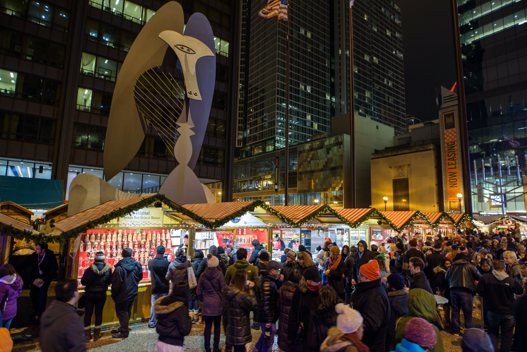 A large crowd gathers at night at the Christkindlmarket in Chicago.