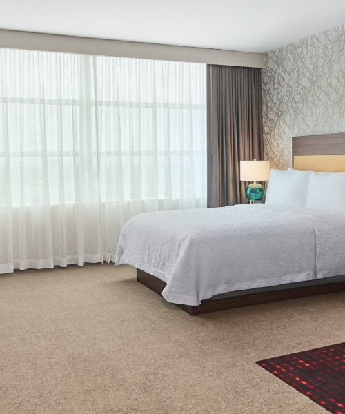 Modern Chicago hotel room at Hilton with queen bed, sofa, desk, and natural light for business and leisure travelers.