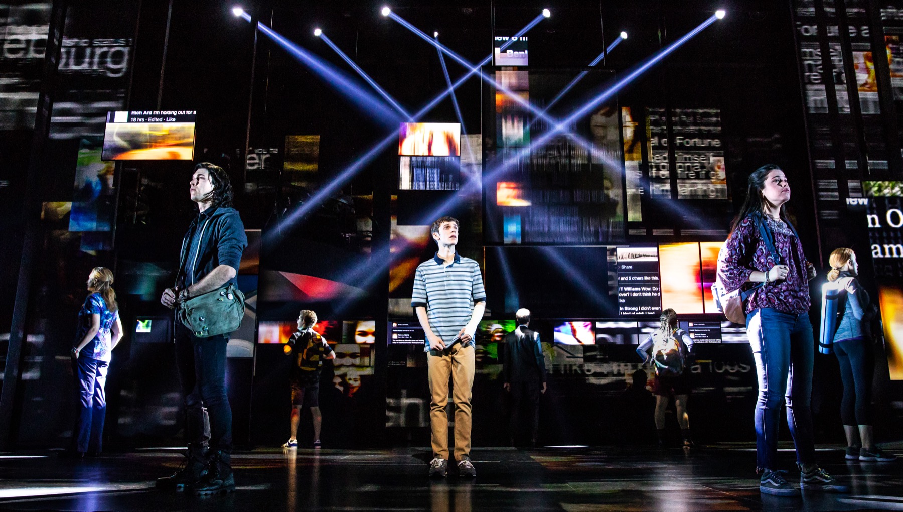 People standing in a circle on a stage with lights and screens