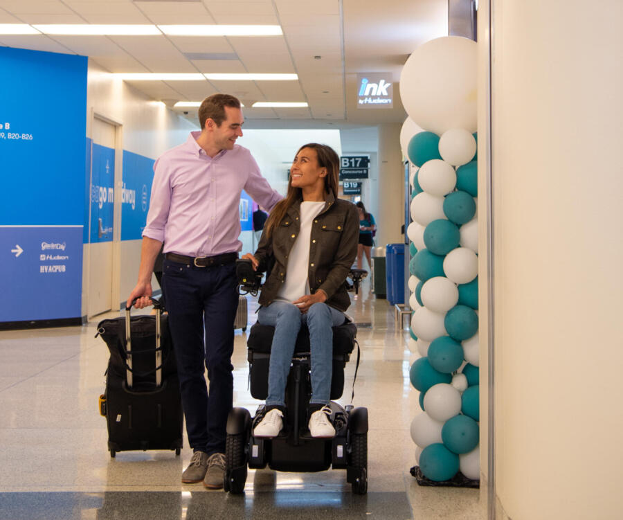 A traveler in a wheelchair waits outside an accessible bathroom