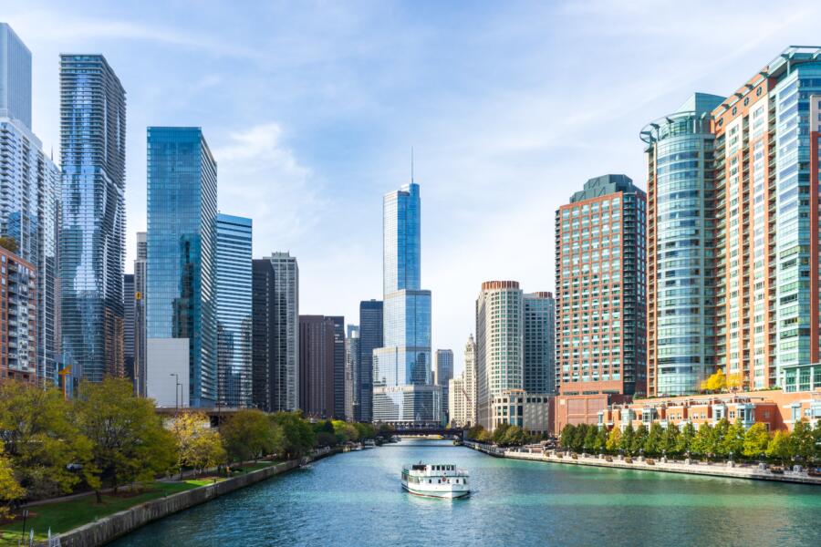 A boat drifts down the Chicago River with the skyline around it