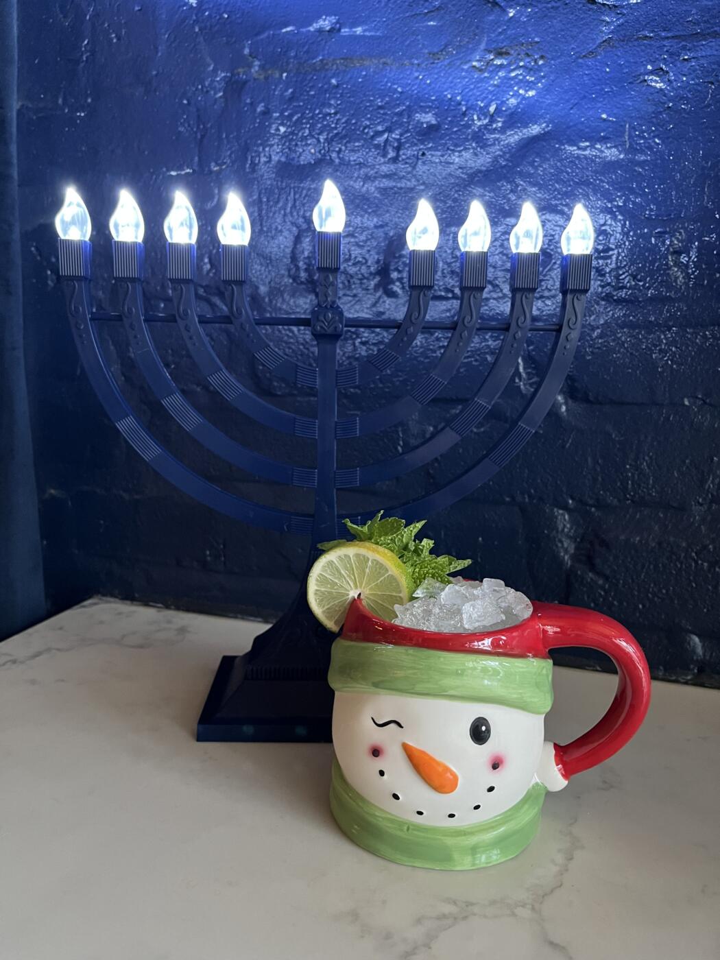 Snowman mug in front of lit Menorah at the Very Dandy Holiday at The Dandy Crown