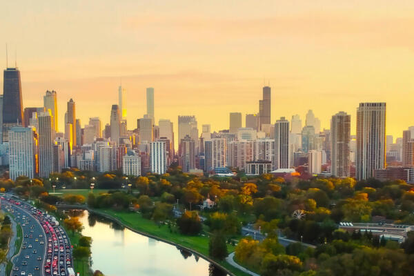 Chicago Cityscape at Sunset with Lakefront View. Aerial view of Chicago skyline at sunset, showing Lake Michigan shoreline, tree-lined parks, and a busy roadway along the waterfront
