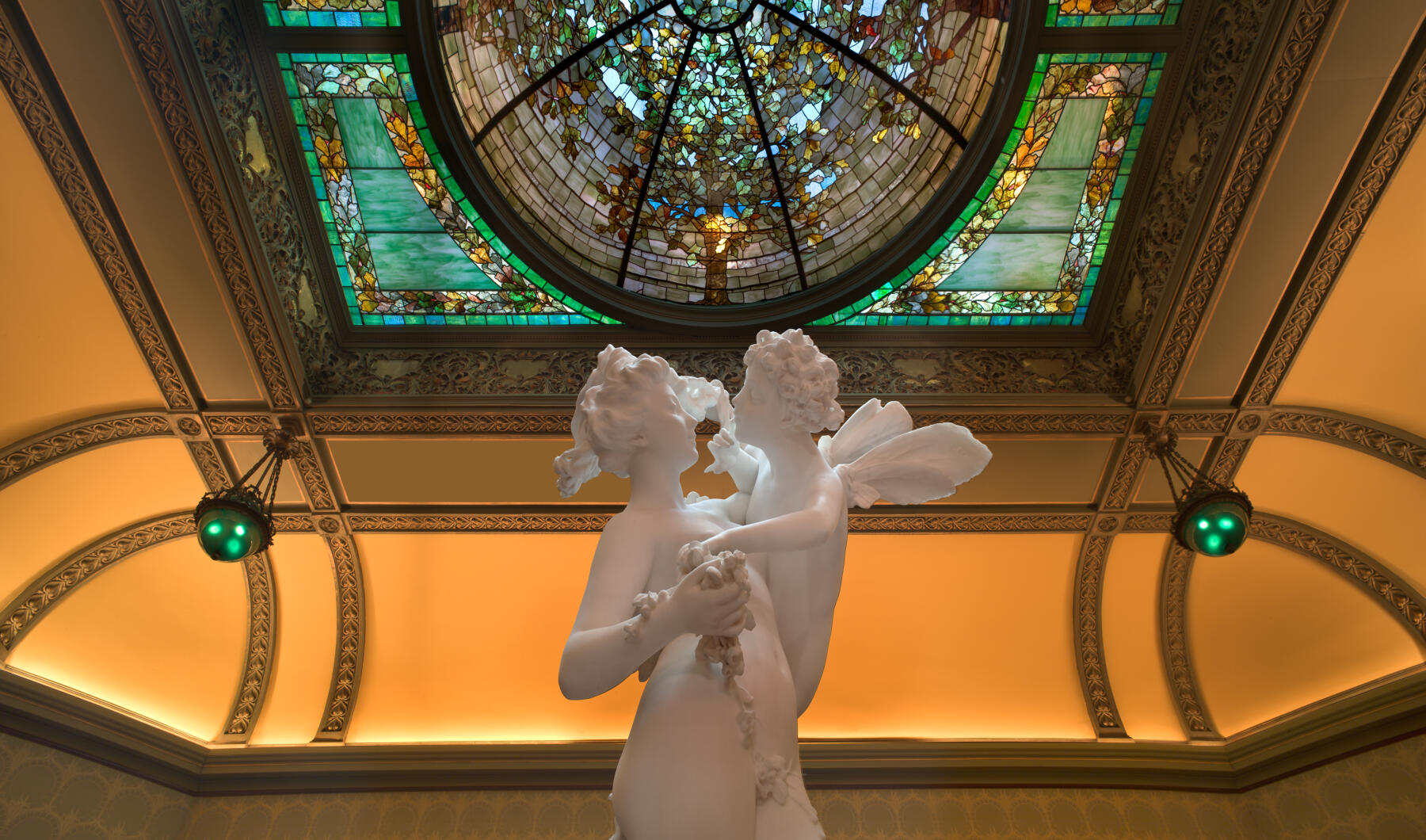 A stained glass ceiling and statue in the Driehaus Museum in Chiccago