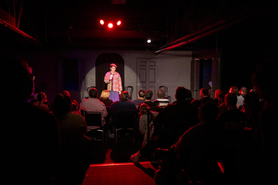 A comedian stands in the spotlight and tells jokes at the iO Improv Chicago.