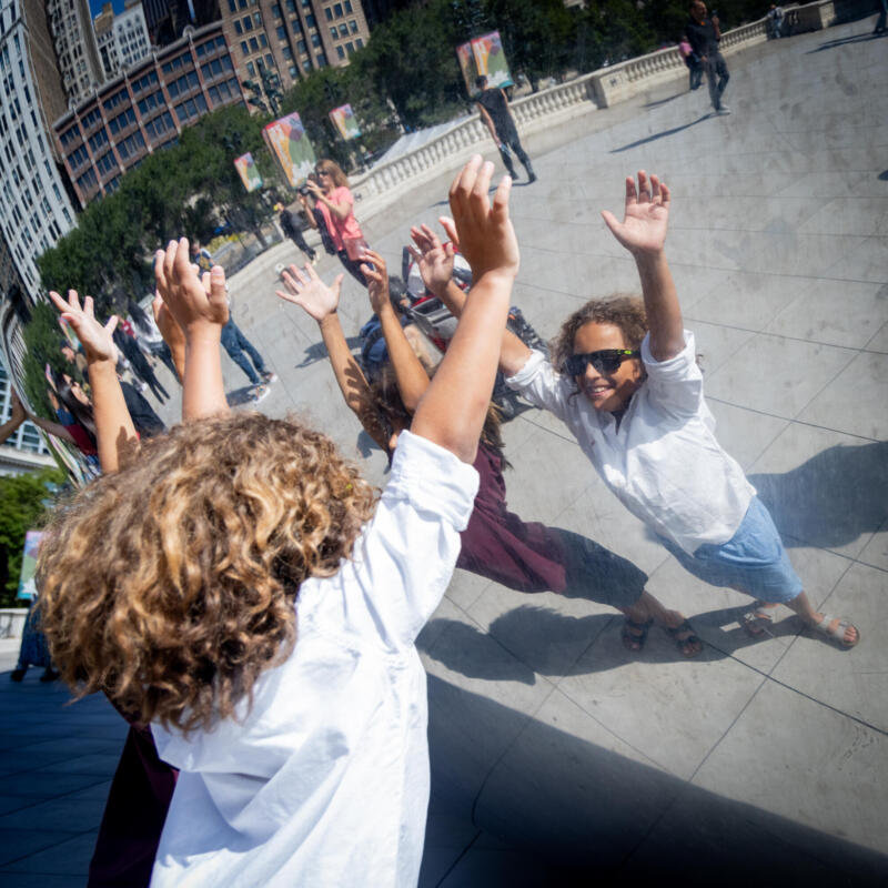 Tourists stand close to the Bean and look at their reflection in Millennium Park.