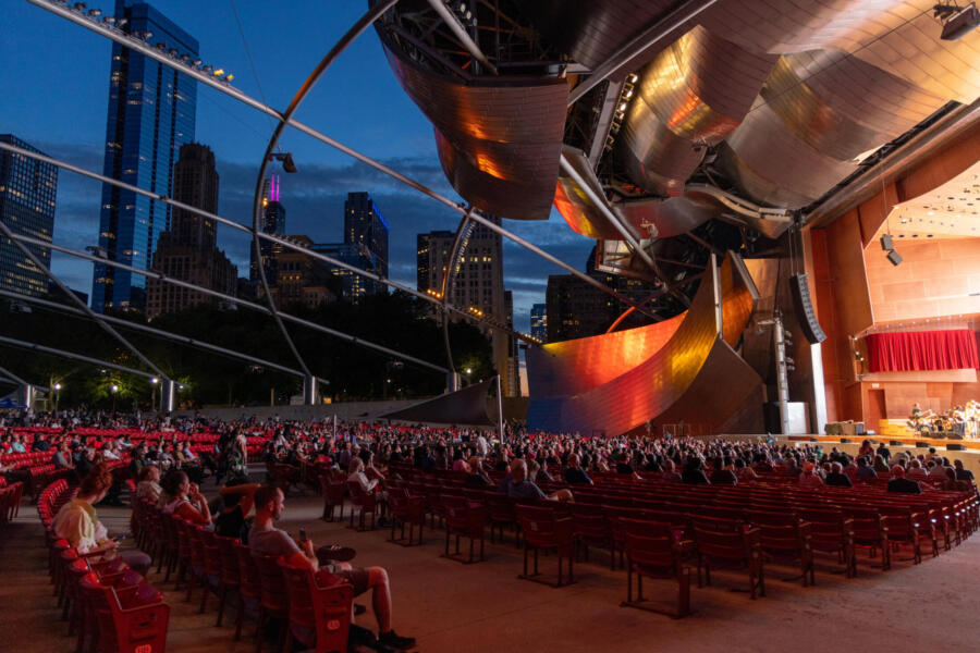 A large crowd of people enjoy a performance at the Millennium Park.