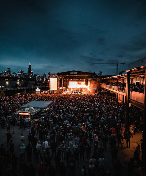 An evening concert outside The Salt Shed with the Chicago skyline in the background