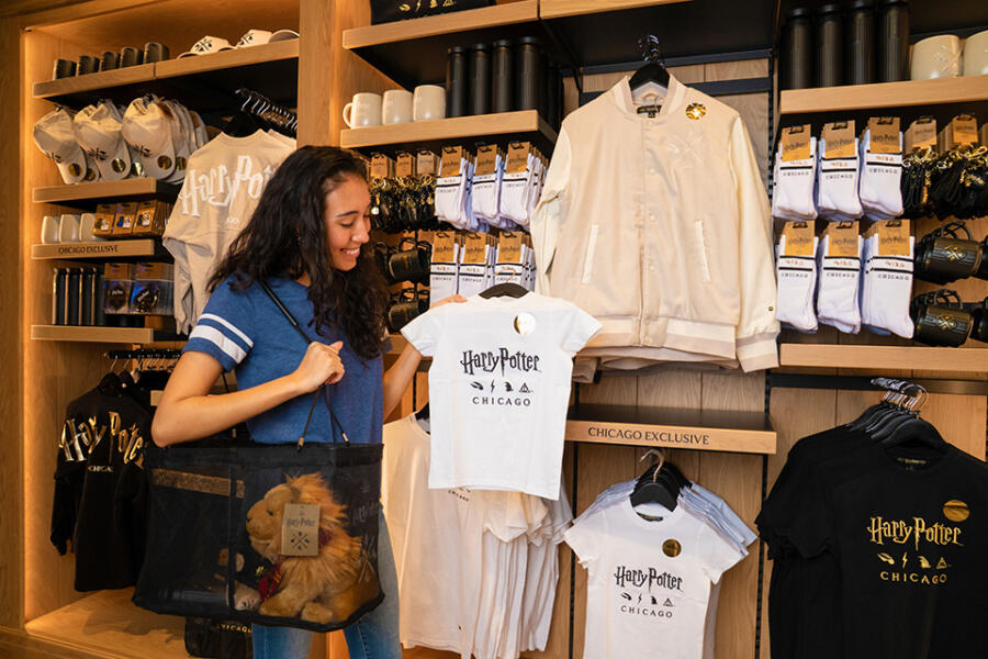 A woman holds up a shirt inside the Harry Potter Shop