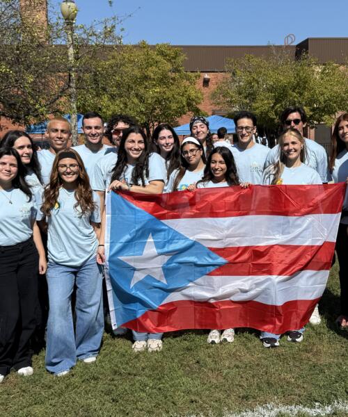 Water Palooza volunteers hold a flag and pose for a photo at Ida B. Wells Preparatory Academy