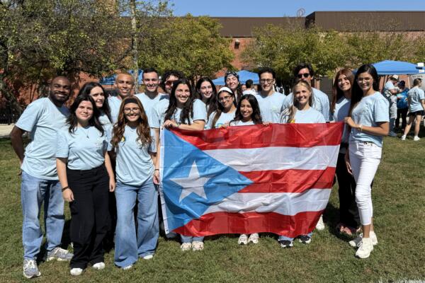 Water Palooza volunteers hold a flag and pose for a photo at Ida B. Wells Preparatory Academy