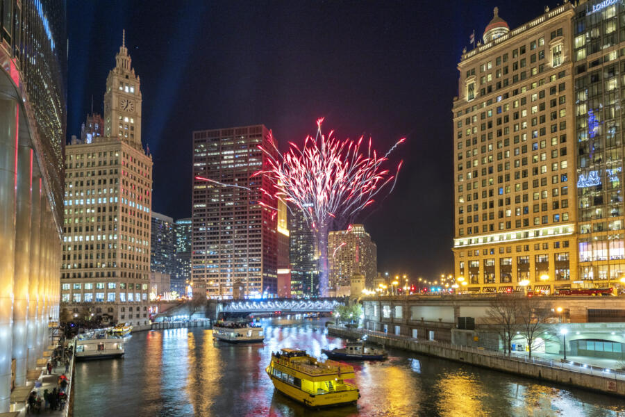 Fireworks explode over the Chicago river on New Year's Eve as boats float down the river