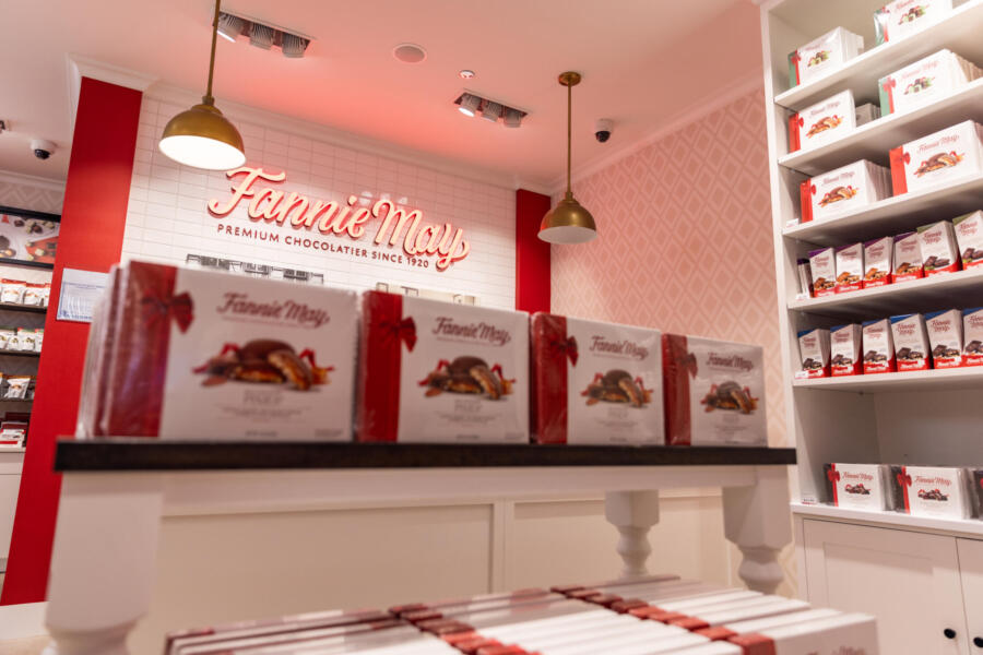 A display of chocolate in red and white boxes on a shelf at Fannie May in Midway International Airport