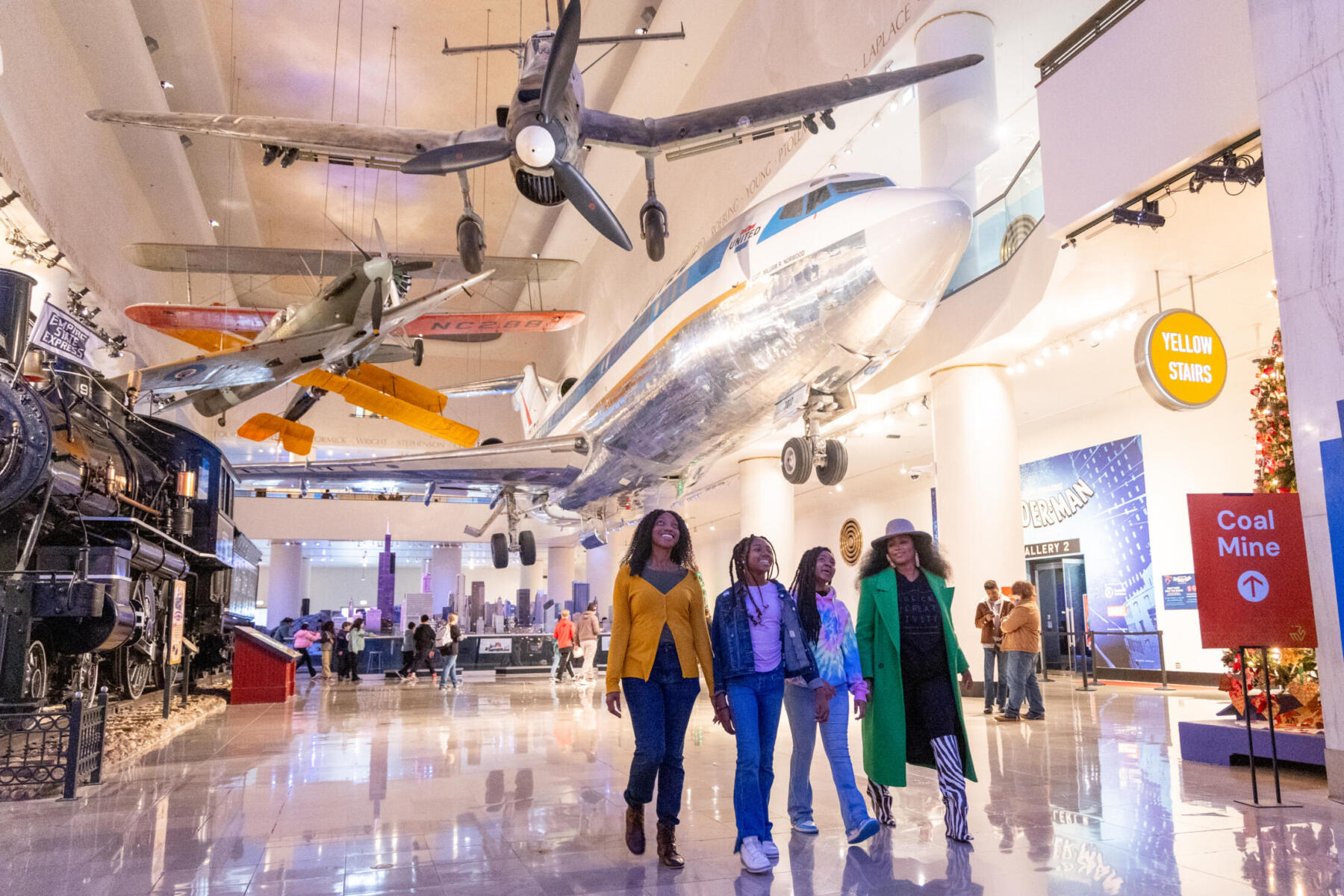 A family walks through the Chicago Hyde Park with airplanes hanging from the ceiling.