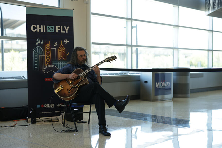 A man plays the guitar in a concourse at Chicago Midway International Airport