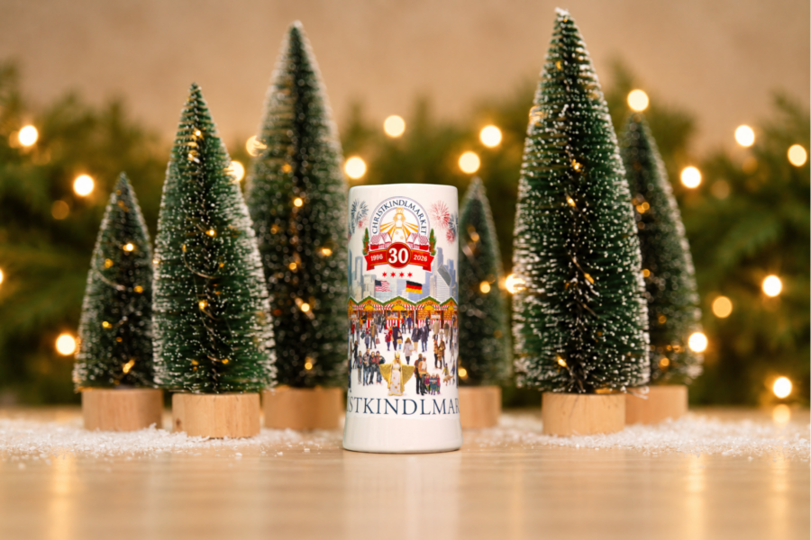 The Christkindlmarket 30th Anniversary Annual Mug placed next to a batch of small Christmas trees.